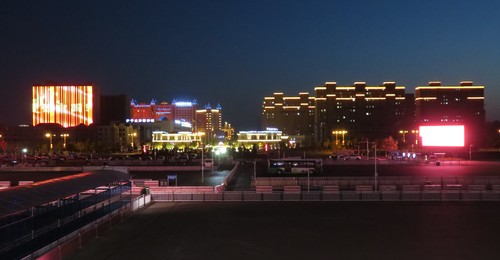 Night view of Yining city from the train station. The large "screen" on the left is actually composed from lights on a building facade, and continuously scrolls the text "I love you China".