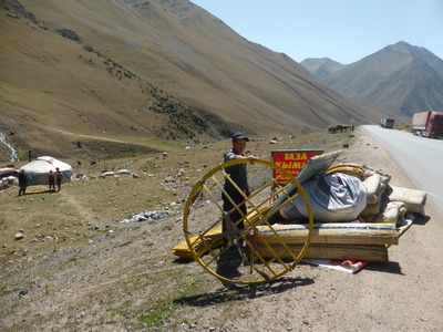A family packing up their yurt along the road from Toktogul up to the Ala-Bel pass, as summer is ending and the high pastures have become drier. The man is holding up the "tunduk", or crown of the yurt, a symbol of family and unity of the Kyrgyz people, and also the symbol in the middle of the Kyrgyz flag.