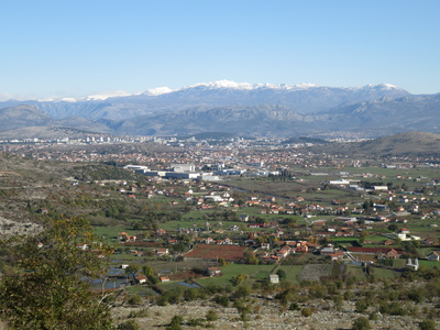 The city of Podgorica, lying in the flat Zeta plain, surrounded by hills and with the snow-clad mountains of the Dinaric Alps in the distance