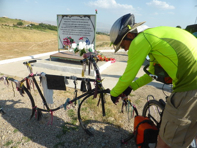 Tying a ribbon onto the memorial for the cyclists who were murdered at this spot near Danghara last year