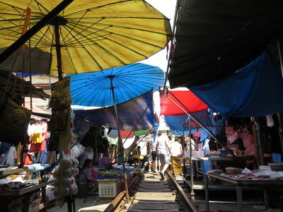 The Maeklong Railway Market in Samut Songkhram, also known as the 'Folding Umbrella Market', as the train passes right through the market eight times a day, forcing vendors to collect in their wares, roll up their awnings, and stand back to allow the train to pass