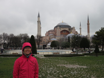 In front of the Hagia Sophia (Ayasofya). Originally built as a Greek Orthodox cathedral in 537 AD, it was converted into an Ottoman imperial mosque in 1453 after Constantinople was conquered by the Ottoman Empire. With the founding of the modern Republic of Turkey, Atatürk secularised the building and it opened as a museum in 1935. The Byzantine architecture of the Hagia Sophia has inspired the design of many other Ottoman mosques after it.